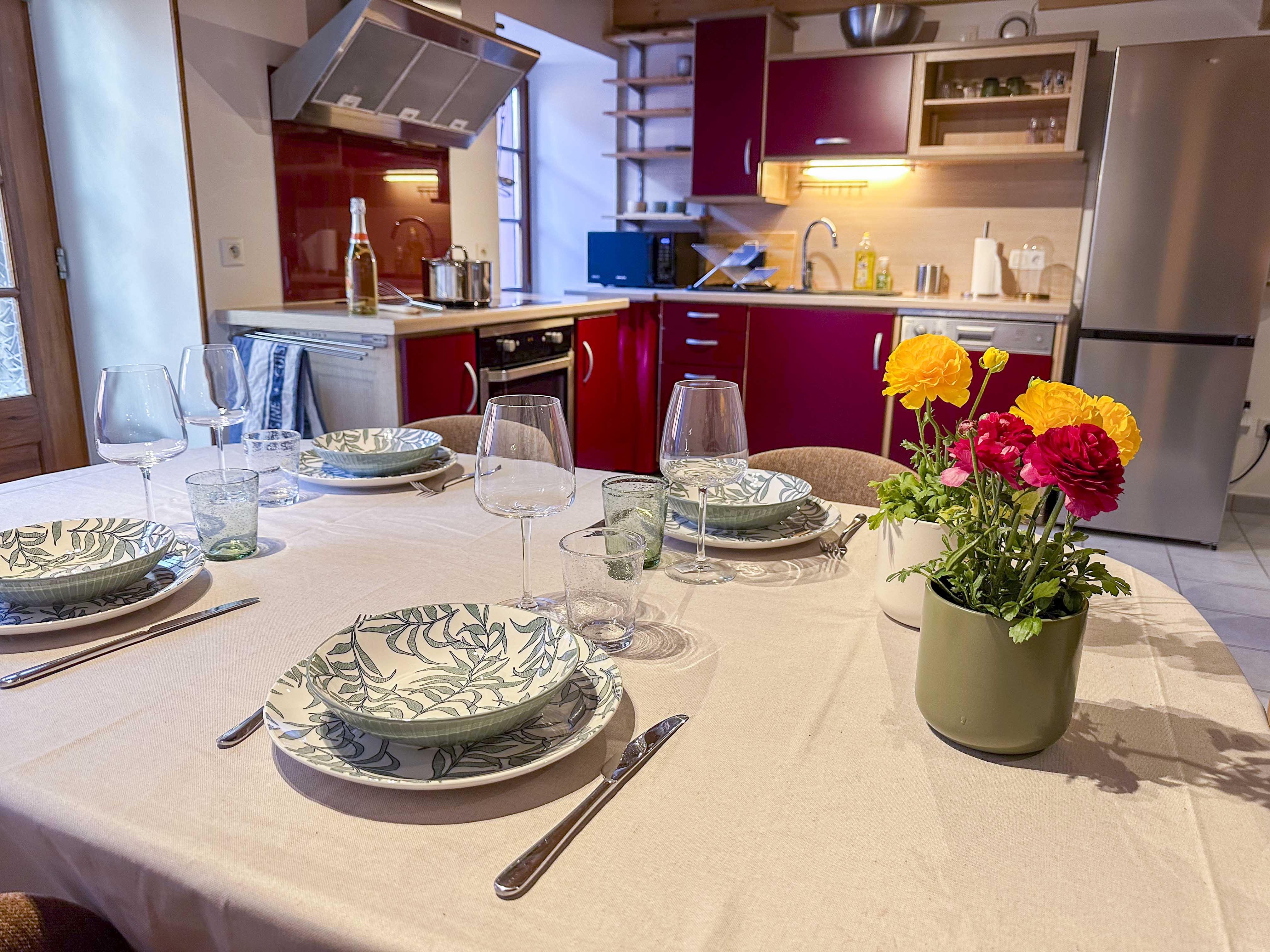 Table dressée avec fleurs, cuisine ouverte en arrière-plan